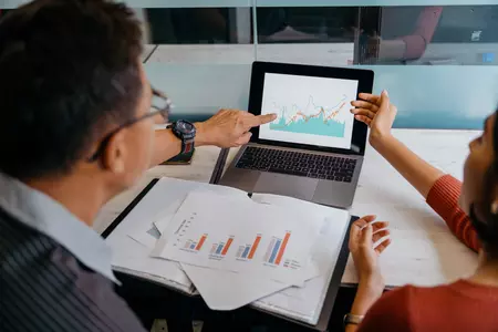 Two people looking at graphs on a laptop 